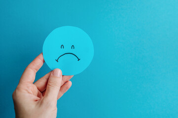 blue circle with sad smile in female hands, sad monday, depression