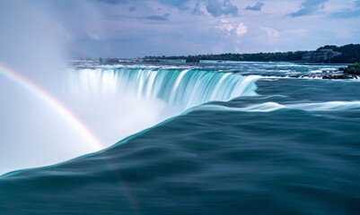 A stunning waterfall with a beautiful rainbow emerging from it