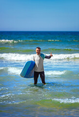 Surfer man learning to surf on foam in the ocean. First surfing lesson. Amateur surfer. Surfing training. Photo for surfing school advertising on social media.