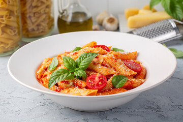 Classic italian pasta penne alla arrabiata with basil and freshly grated parmesan cheese on dark table. Penne pasta with chili sauce arrabbiata.