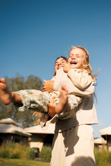 Mom throws baby in her arms girl child laughs. Family outdoor recreation.