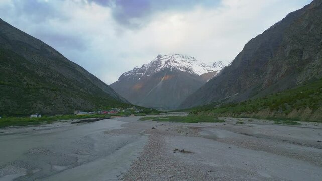 A stunning aerial view of Jispa village in Himachal Pradesh, surrounded by majestic mountains, a meandering river, and colorful campsites amidst lush greenery.