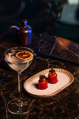 A luxury table features two elegant pieces of sushi, garnished with fresh herbs and a glass of white vermouth.