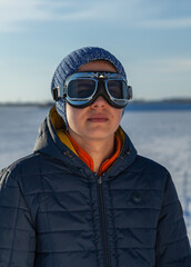 Portrait of yang man with protective eyeglasses ready for travel.
Nice boy with winter snow goggles. An extreme type of winter sport. The concept of endurance in the way.