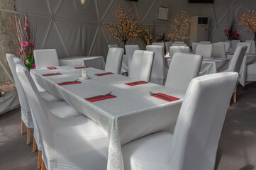 Inside of city cafe. Modern Cafe restaurant interior with white chairs around a round coffee table. Luxury restaurant interior. Empty tables at a restaurant. Modern white coffee shop interior.