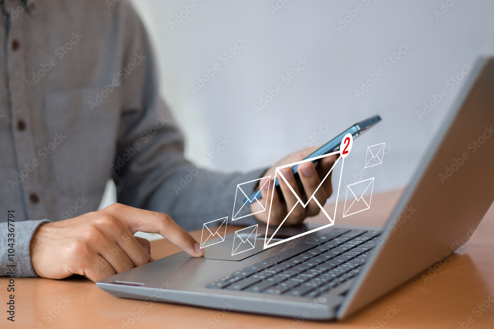 Wall mural man uses laptop with notification icon of two new email messages. communication business technology.