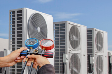 Air conditioning, HVAC service technician using gauges to check refrigerant and add refrigerant.
