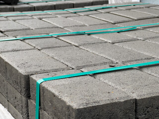 Stacked neatly, gray brick pavers are prepared for sidewalk installation in an urban area, showcasing the materials used in paving projects