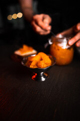 Pumpkin jam in a jar. Pumpkin jam spread on bread. The cook prepares pumpkin jam. Pumpkin jam on a black background