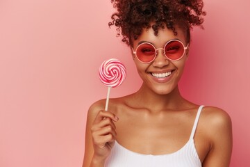 A woman holds a colorful lollipop in front of her face, wearing trendy sunglasses