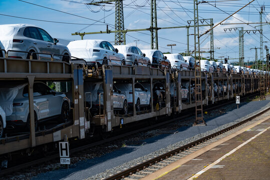 train carrying multiple new Porsche macan SUVs, some covered and some uncovered, awaiting destination, Bebra, Germany - August 15, 2024