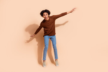 Energetic young man striking a playful pose against a neutral beige background