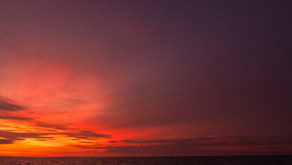 Fototapeta premium Dusk, Sunset sky clouds over sea in the evening on twilight with dark Blue, Purple, Pink, Red and Orange sunlight, Horizon sea sky sun down landscape backgrounds in Autumn