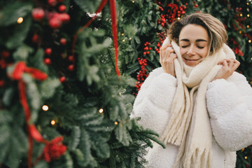 Young beautiful woman enjoying Christmas decorations on city street.