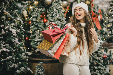 Young beautiful womam enjoying Christmas shopping on a decorated street.