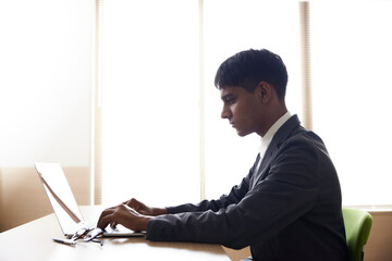 パソコンを使用して仕事をする若いインド人の技能実習生