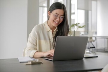Smiling Asian Woman Working on Laptop at Home Office