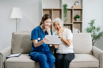 Asian caregiver doctor examine older patient woman therapist nurse at nursing home taking care of senior elderly woman sit on sofa.Medical service concept.