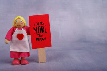 Wooden figure holding a red banner with a positive phrase, inspiring optimism and encouragement,...