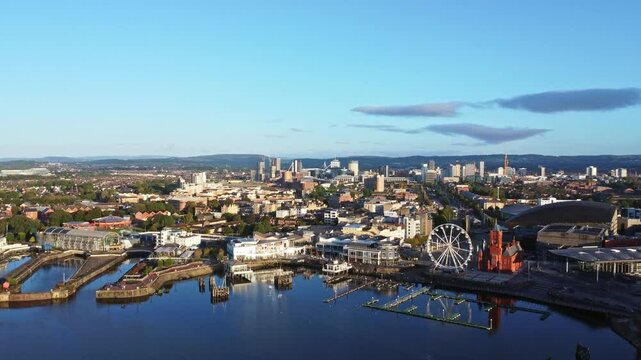 Aerial drone footage of Cardiff Bay area at sunrise, with the Cardiff city centre skyline visible in the distance. High altitude push in shot.