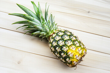 Pineapple is sitting on a wooden table.