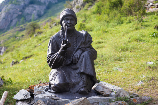 Altai Republic, Russia - June 14, 2024: A fragment of a sculptural ensemble dedicated to the indigenous people of Altai on Chuysky trakt - elderly Altai woman with a tobacco pipe. Installed in 2023