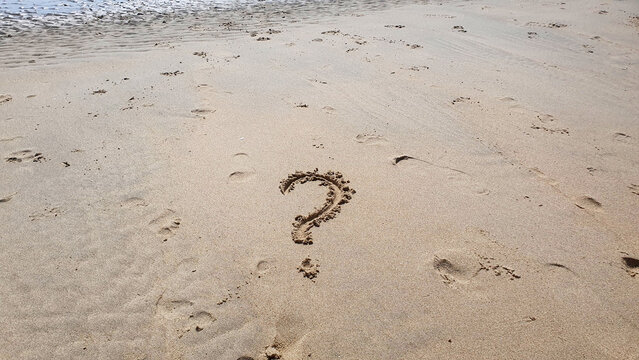 Question word on yellow sand background on the beach.