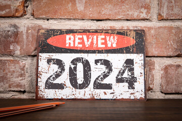 Review 2024 Concept. Metal sign with inscription on wooden texture office desk