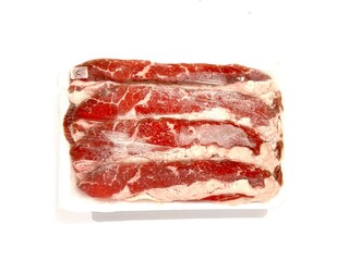 Pack of frozen fresh and raw red beef slice with fat in plastic wrap isolated on white background