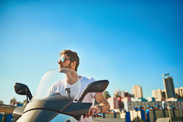 Fototapeta premium Motorcycle, travel and urban with man in city for thinking, freedom and transportation. Journey, summer vacation and speed with person driving on motorbike for vintage driver, adventure and explore