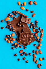 Chocolate with nuts and its ingredients on blue background top view