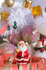 A small figurine of Santa Claus in a red and white suit holding a green sack,