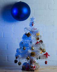 Small white Christmas tree decorated with golden and pine cones, and miniature Santa figurines