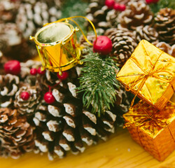 Two small golden gift boxes stacked, set against a blurred background of a festive Christmas wreath.