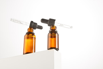 Two pipettes with serum are on brown open bottles necks.