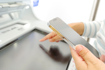 スマホを見ながらATMを操作する女性