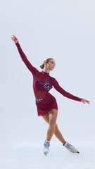 Young female skater performing in graceful pose, extending her arms outward, gliding smoothly on ice. Young girl in motion, dancing. Concept of professional sport, performance. Copy space, ad © master1305