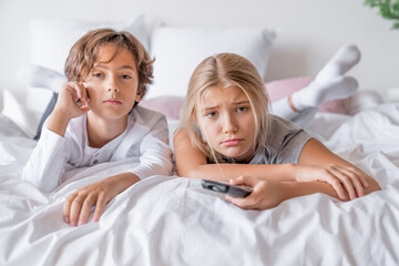 Bored tired exhausted siblings brother and sister boy and girl in pajamas lying in bedroom at home...