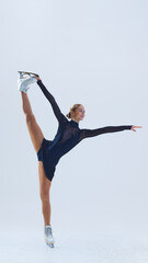 Graceful and talented young girl, figure skater in black stage costume in motion, dancing isolated...