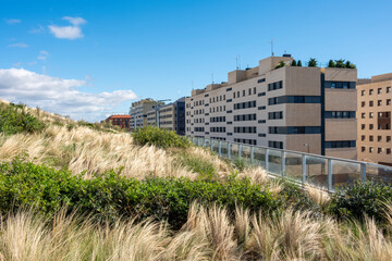 A contemporary apartment building surrounded by lush grasses under a beautiful blue sky, representing urban nature, tranquility, and modern lifestyle balance in Logrono Spain