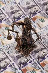 Sculpture of Themis against the background of $100 bills