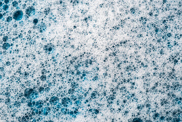Background and pattern. White soap foam with bubbles, texture on blue tile background.