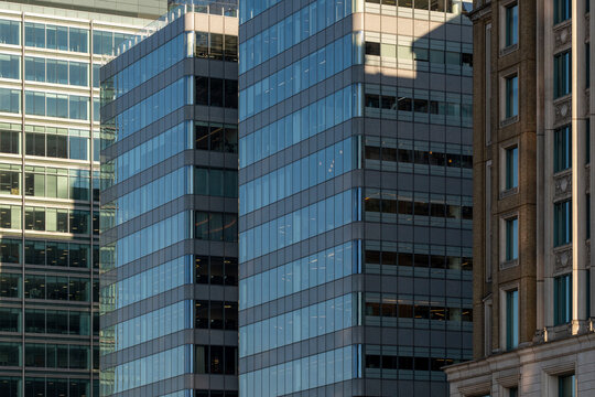 An urban scene with multiple skyscrapers showcasing reflective blue glass windows, representing the bustling energy and grandeur of a modern city.
