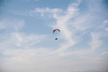 A paraglider flies over the sea and mountains during sunset. Extreme sports and adrenaline