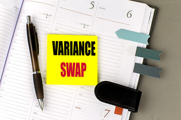Variance swap concept with yellow sticky note, pen, and planner on a desk
