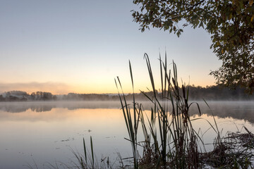 Blurred landscape with a lake in the morning fog, fog trailing over the lake