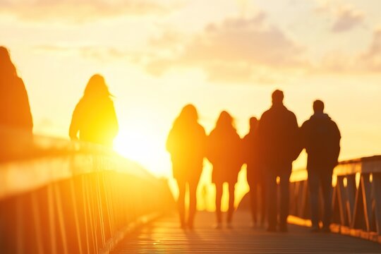 Silhouetted group walking on bridge at sunset
