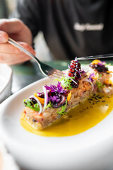 Close-up of a gourmet dish with vibrant garnishes on a white plate, highlighting fine dining. The presentation emphasizes the elegance and artistry of culinary craftsmanship