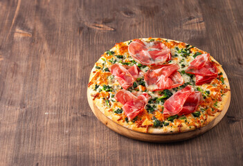 Pizza with prosciutto, ham, arugula, spinach, tomatoes, pesto, cheese and parmesan. Italian cuisine. 