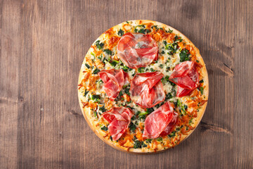 Pizza with prosciutto, ham, arugula, spinach, tomatoes, pesto, cheese and parmesan. Italian cuisine. 